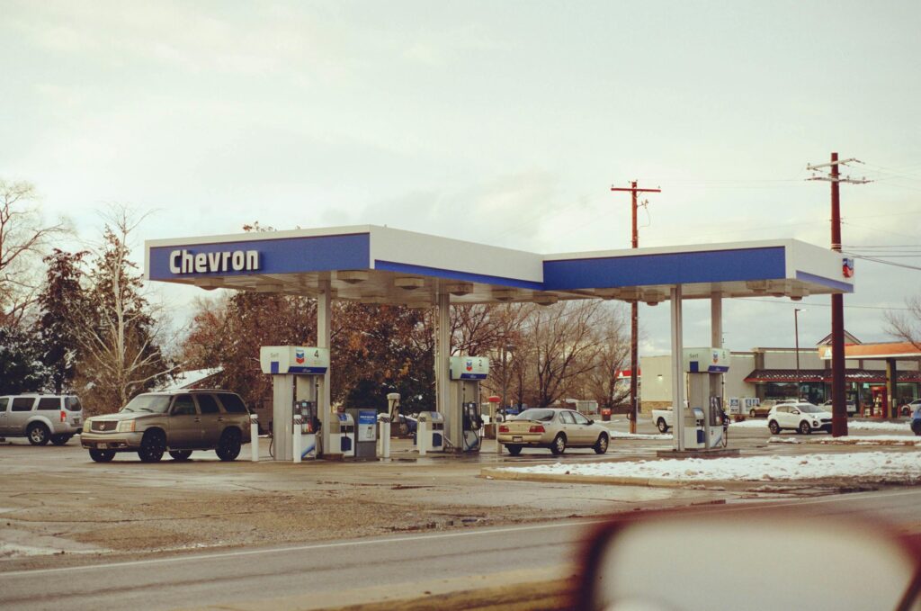 A Chevron gas station with several vehicles parked on a snowy day, emphasizing travel and fuel.